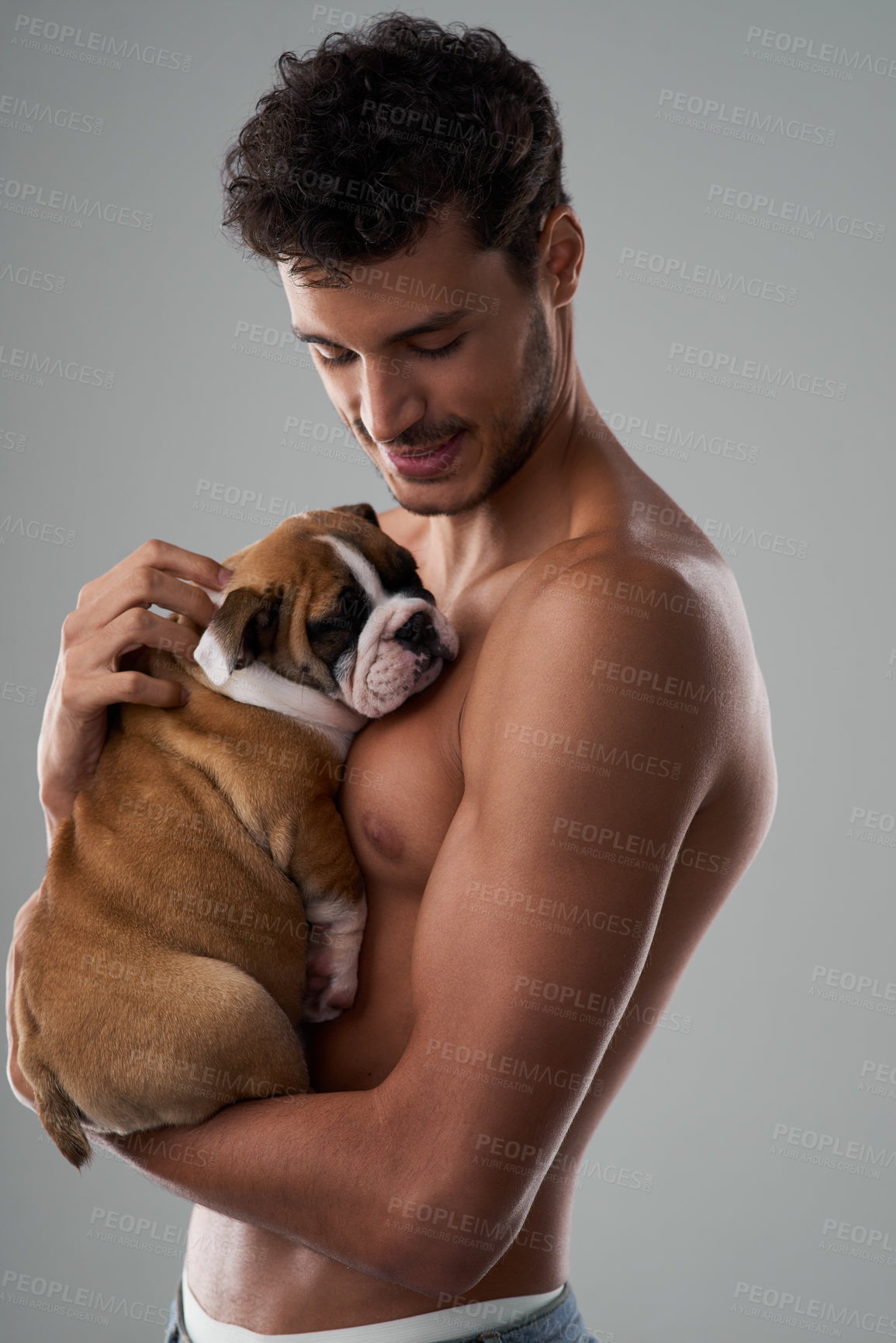 Buy stock photo Studio shot of a handsome young man posing with his puppy against a grey background