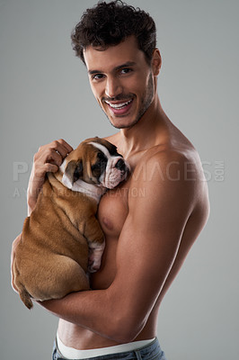 Buy stock photo Studio shot of a handsome young man posing with his puppy against a grey background