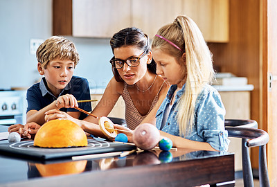 Buy stock photo Shot of a mother helping her two young children with a school project at home