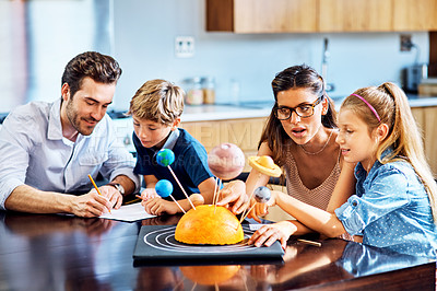 Buy stock photo Shot of parents helping their kids with a school project at home