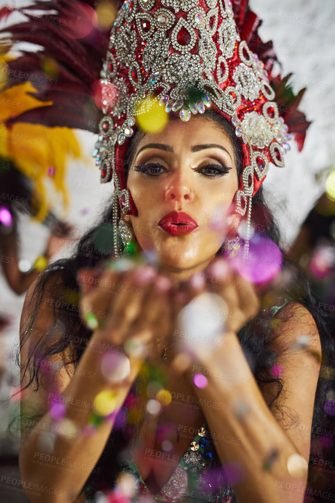 Buy stock photo Shot of a samba dancer blowing confetti from her hands while performing in a carnival