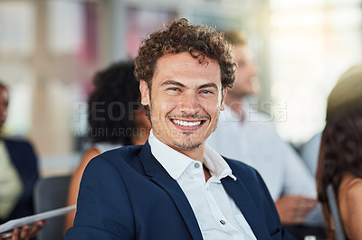 Buy stock photo Cropped portrait of a handsome young businessman attending a seminar with his colleagues