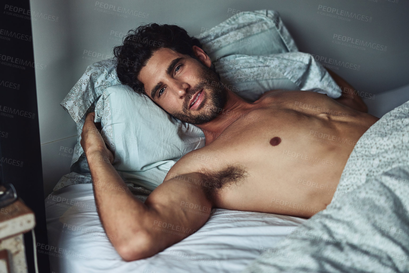 Buy stock photo Cropped shot of a handsome young shirtless man lying in bed at home