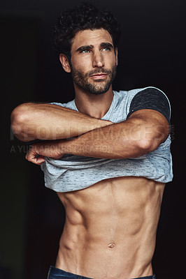 Buy stock photo Cropped shot of a handsome young shirtless man undressing at home