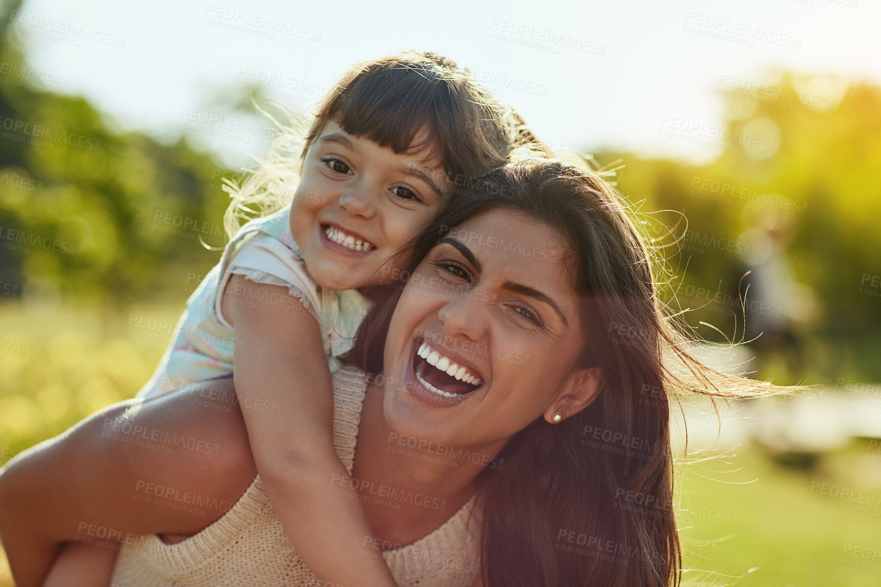 Buy stock photo Shot of an adorable little girl and her mother enjoying a piggyback ride in the park