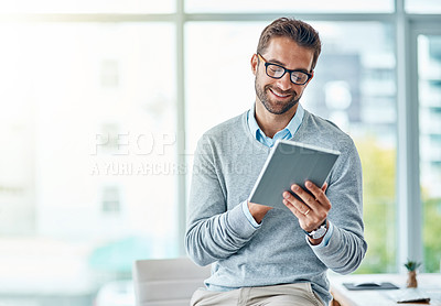 Buy stock photo Shot of a young businessman using a digital tablet in an office