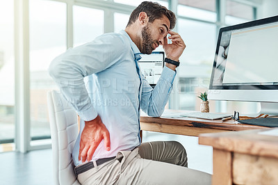Buy stock photo Shot of a young businessman suffering with back pain while working in an office