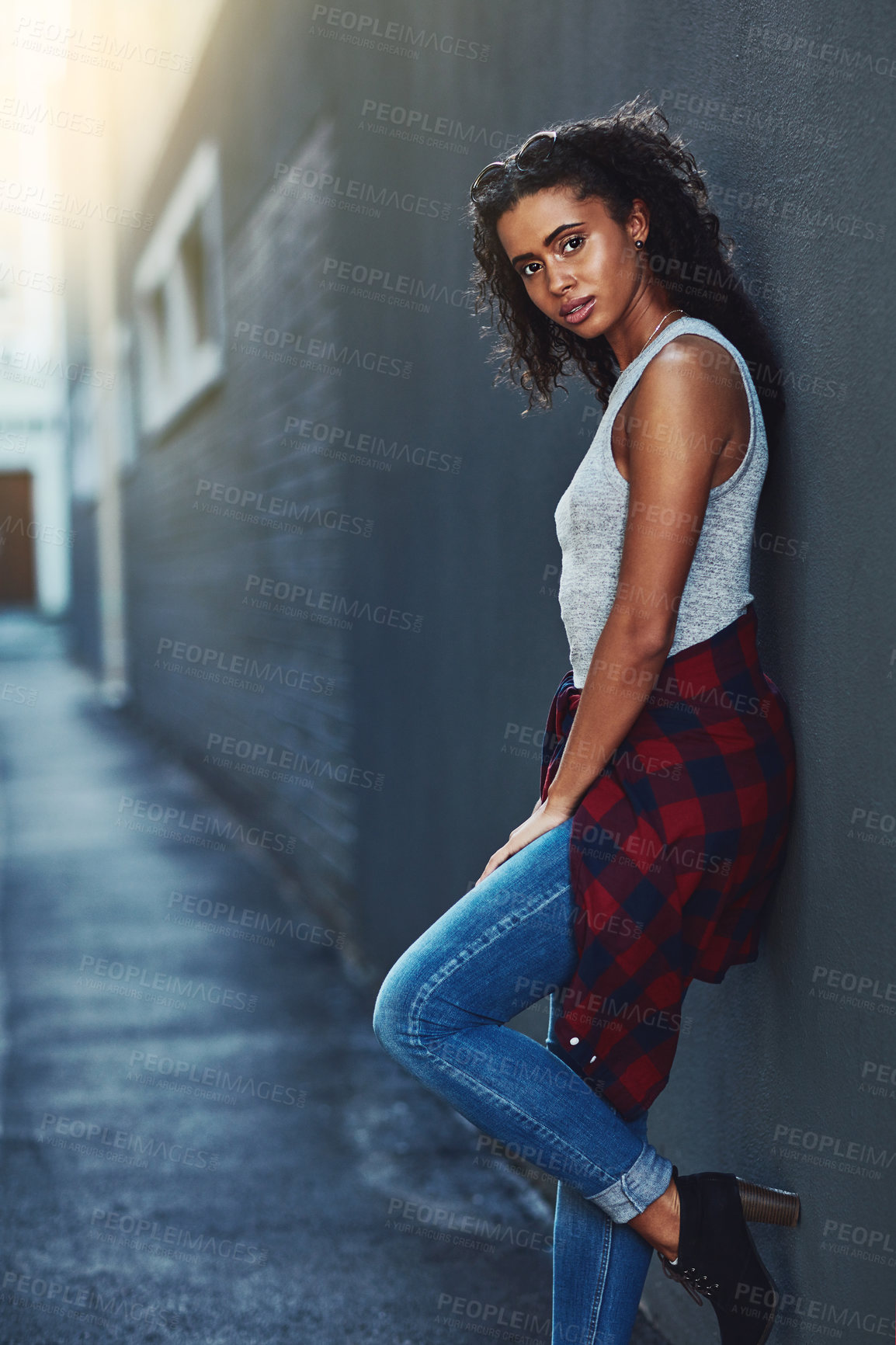 Buy stock photo Shot of an attractive young woman posing against a wall in the city