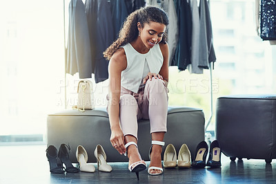 Buy stock photo Shot of an attractive young woman trying on shoes while on a shopping spree in a boutique