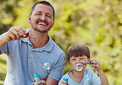 Buy stock photo Portrait of a father and his son blowing bubbles together outdoors