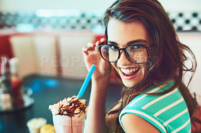 Buy stock photo Cropped portrait of an attractive young woman enjoying a milkshake in a retro diner