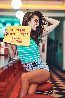Buy stock photo Cropped shot of an attractive young woman holding up a sign in a retro diner