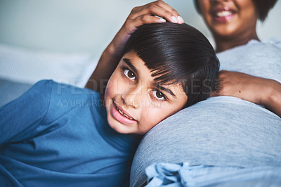 Buy stock photo Cropped portrait of an adorable little boy lying on his mother's lap while trying to hear the baby