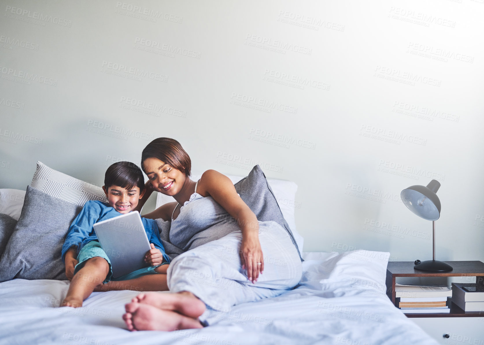 Buy stock photo Full length shot of an adorable little boy and his pregnant mother using a laptop while relaxing on her bed