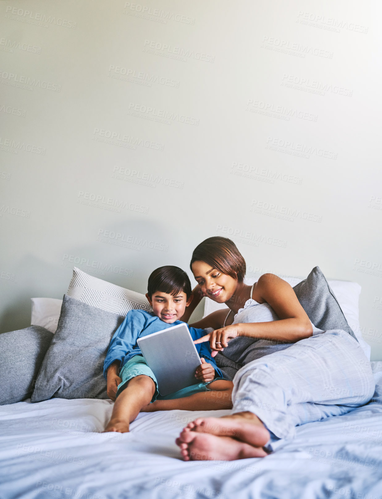 Buy stock photo Full length shot of an adorable little boy and his pregnant mother using a laptop while relaxing on her bed