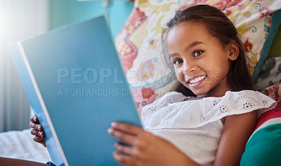 Buy stock photo Portrait of an adorable little girl reading a book at home