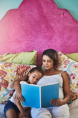 Buy stock photo Shot of a mother reading a story to her little daughter at home