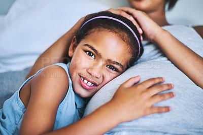 Buy stock photo Portrait of a cheerful little girl relaxing on the bed with her pregnant mother at home during the day