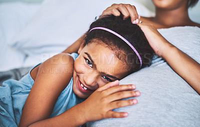 Buy stock photo Portrait of a cheerful little girl relaxing on the bed with her pregnant mother at home during the day