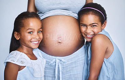 Buy stock photo Portrait of two cheerful little girls  standing next to their pregnant mother at home during the day