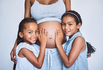Buy stock photo Portrait of two cheerful little girls  standing next to their pregnant mother at home during the day