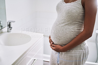 Buy stock photo Closeup shot of a pregnant woman standing in the bathroom at home