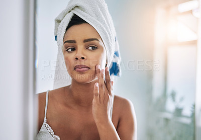 Buy stock photo Shot of an attractive young woman applying moisturizer to her face in the bathroom