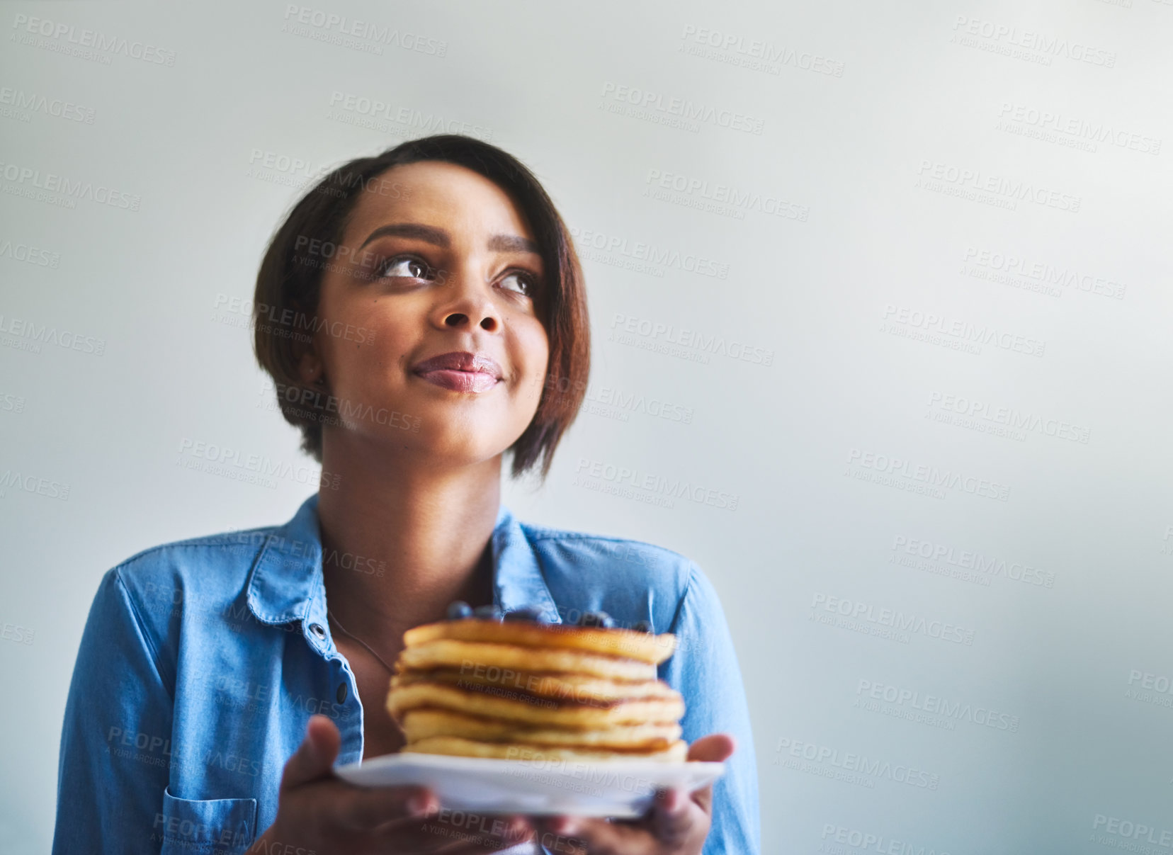 Buy stock photo Shot of an attractive young woman eating delicious pancakes at home