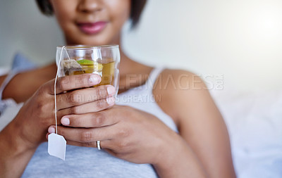 Buy stock photo Cropped shot of a young woman relaxing at home with a glass of tea