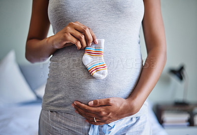 Buy stock photo Cropped shot of a pregnant woman holding a baby’s sock in front of her belly