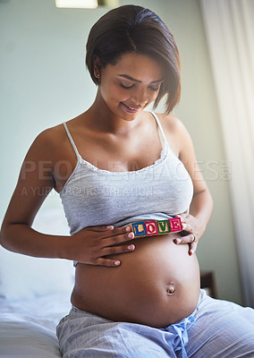 Buy stock photo Shot of a young pregnant woman with wooden blocks on her belly that spell the word love