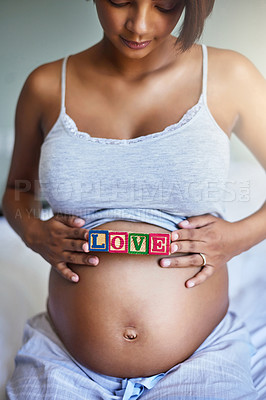 Buy stock photo Shot of a young pregnant woman with wooden blocks on her belly that spell the word love