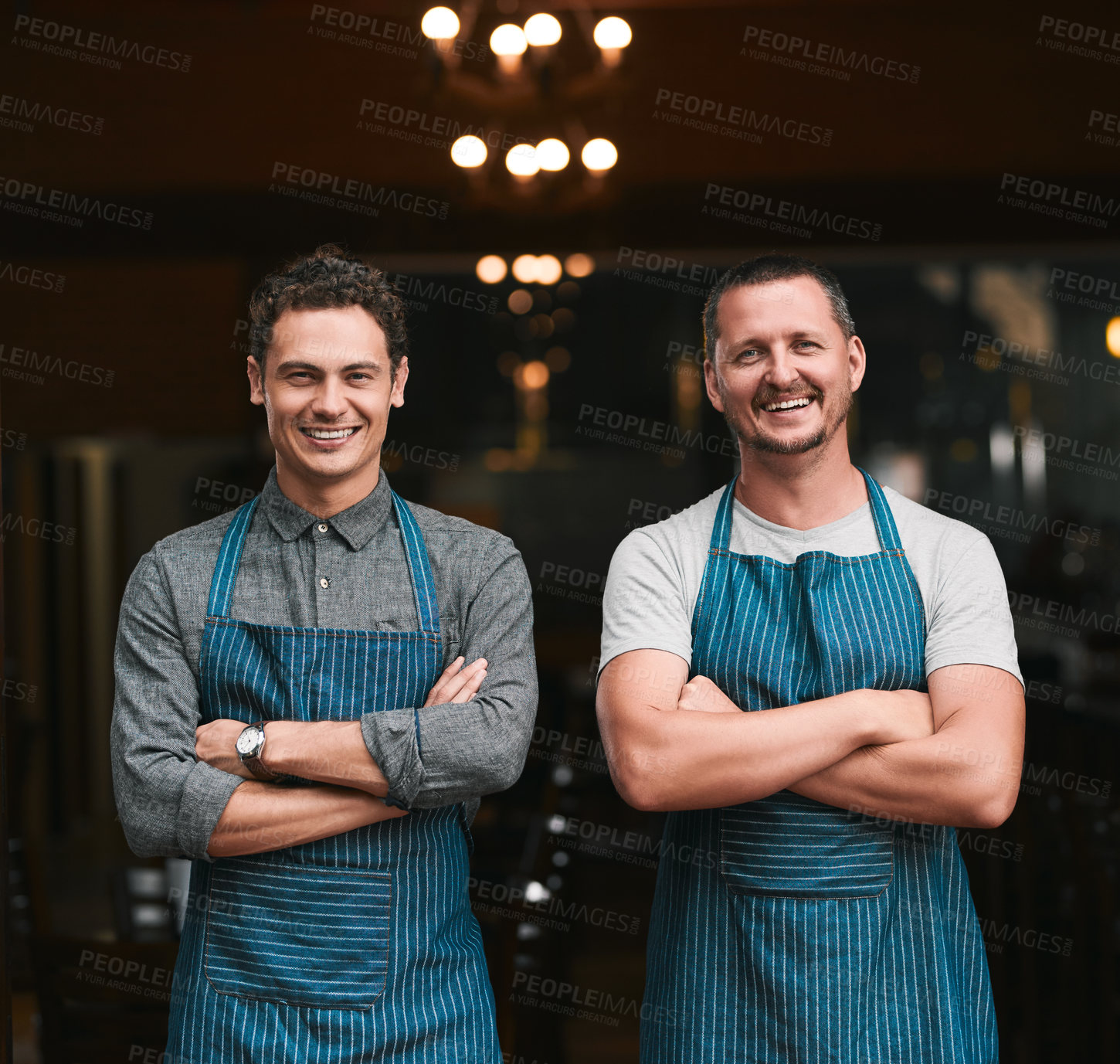 Buy stock photo Portrait of two cheerful young businessmen standing with arms folded in front of a beer brewery outside during the day