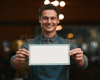 Buy stock photo Portrait of a cheerful young man holding a sign while standing inside of a beer brewery during the day