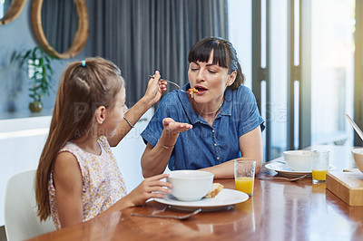 Buy stock photo Shot of a mother enjoying a meal with her little daughter at home