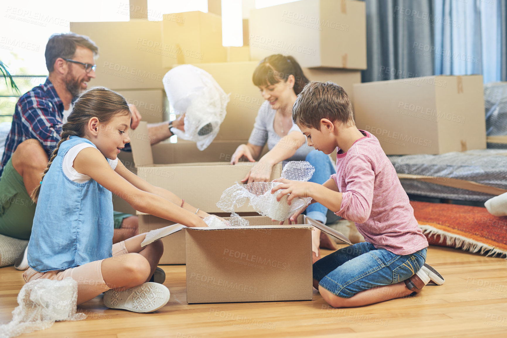 Buy stock photo Shot of a family of four helping each other pack boxes on moving day