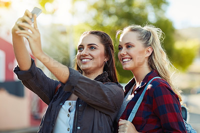 Buy stock photo Cropped shot of two beautiful female friends taking a selfie in the city