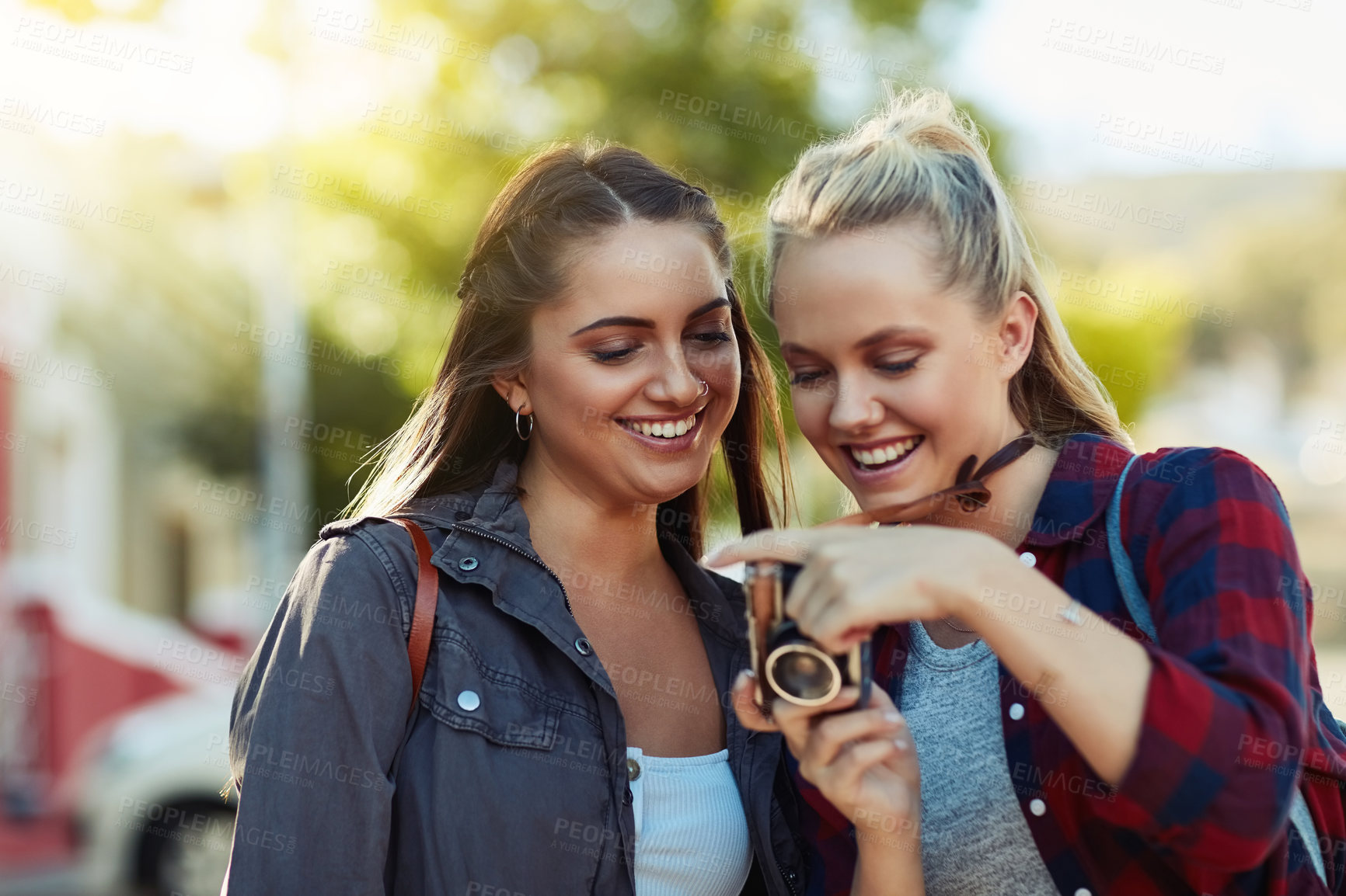 Buy stock photo Cropped shot of two beautiful female friends looking at photographs on a camera in the city