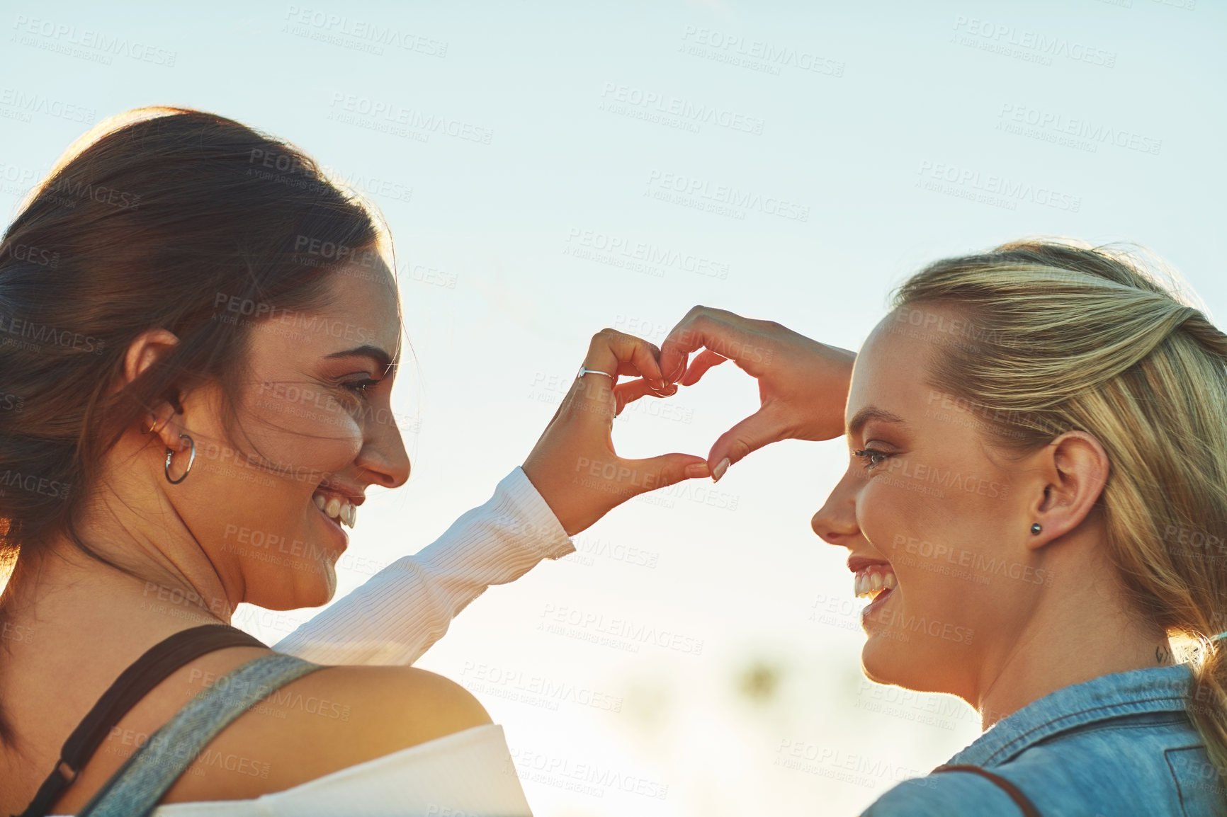 Buy stock photo Rearview shot of two beautiful female friends making a heat shape with their hands in nature