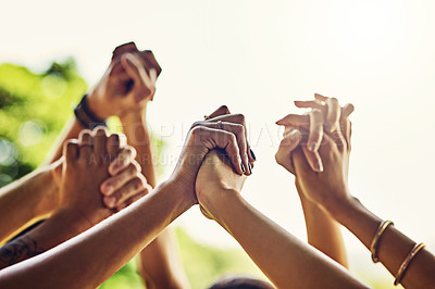 Buy stock photo Closeup shot of an unrecognizable group of people holding hands with their arms raised outdoors