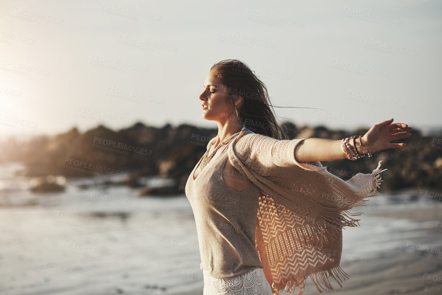 Buy stock photo Shot of an attractive young woman standing with her arms outstretched at the beach