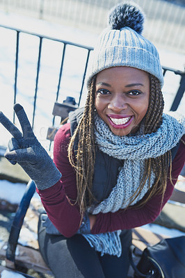 Buy stock photo Shot of a beautiful young woman making a peace gesture on a snowy day outdoors