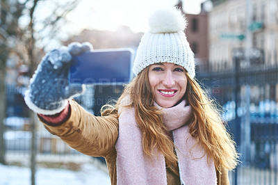 Buy stock photo Shot of an attractive young woman taking a selfie in the snow outside