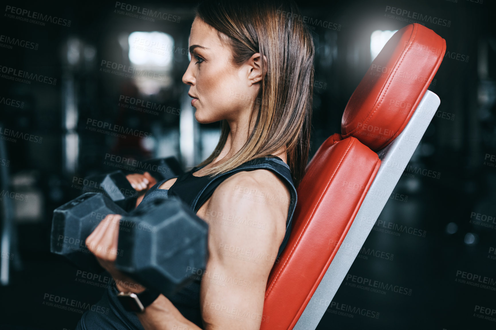 Buy stock photo Shot of a young woman working out with weights in a gym