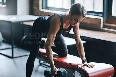 Buy stock photo Shot of a young woman working out with weights in a gym