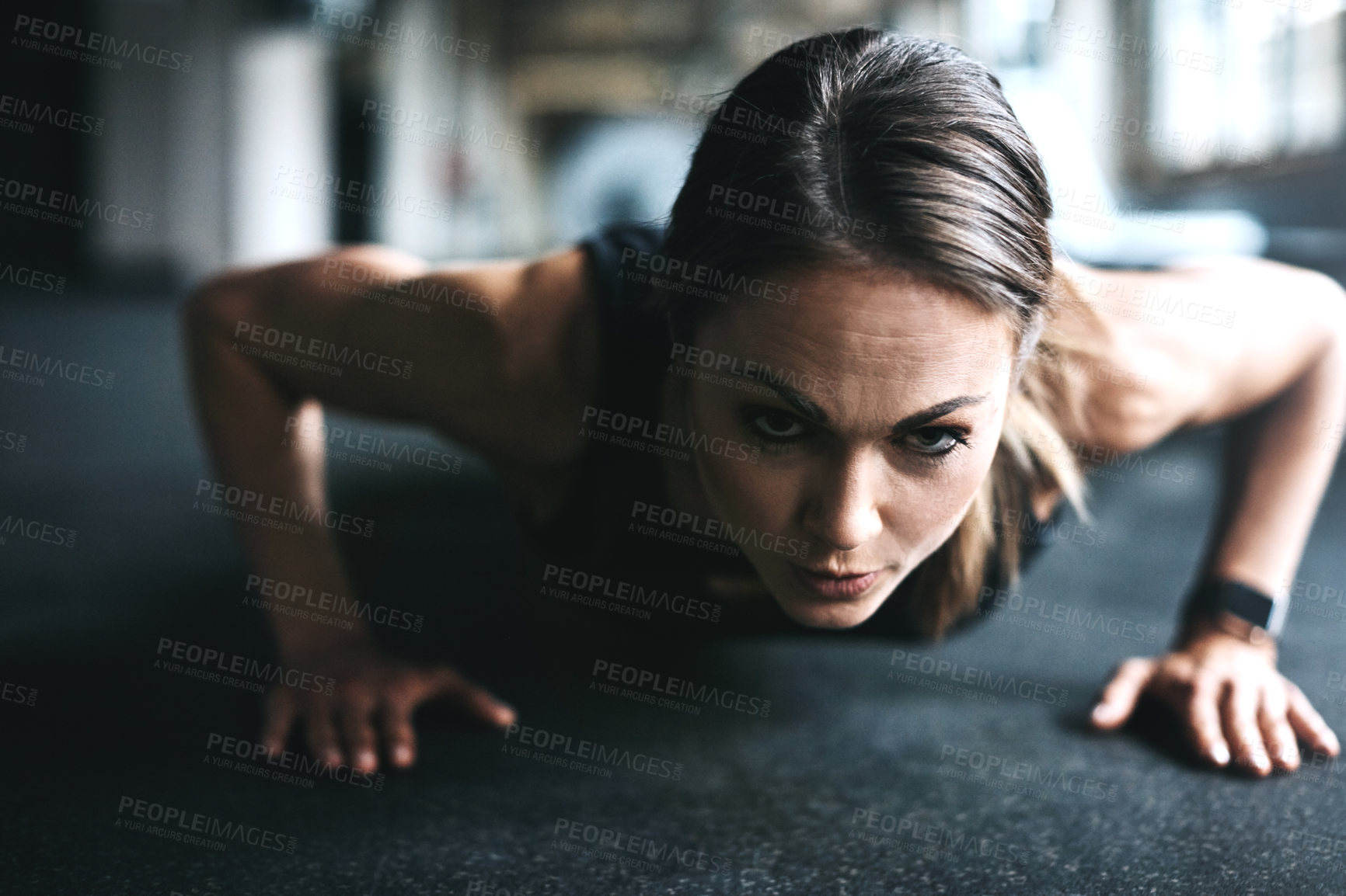 Buy stock photo Shot of an attractive young woman doing push ups in a gym