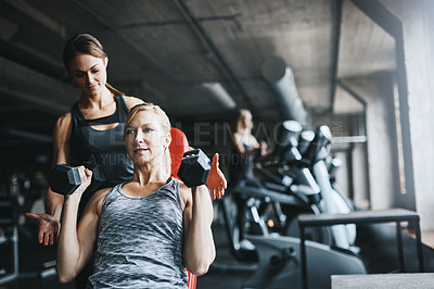 Buy stock photo Cropped shot of a mature woman lifting weights with a female instructor at the gym
