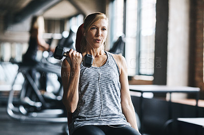 Buy stock photo Shot of a mature woman lifting weights at the gym