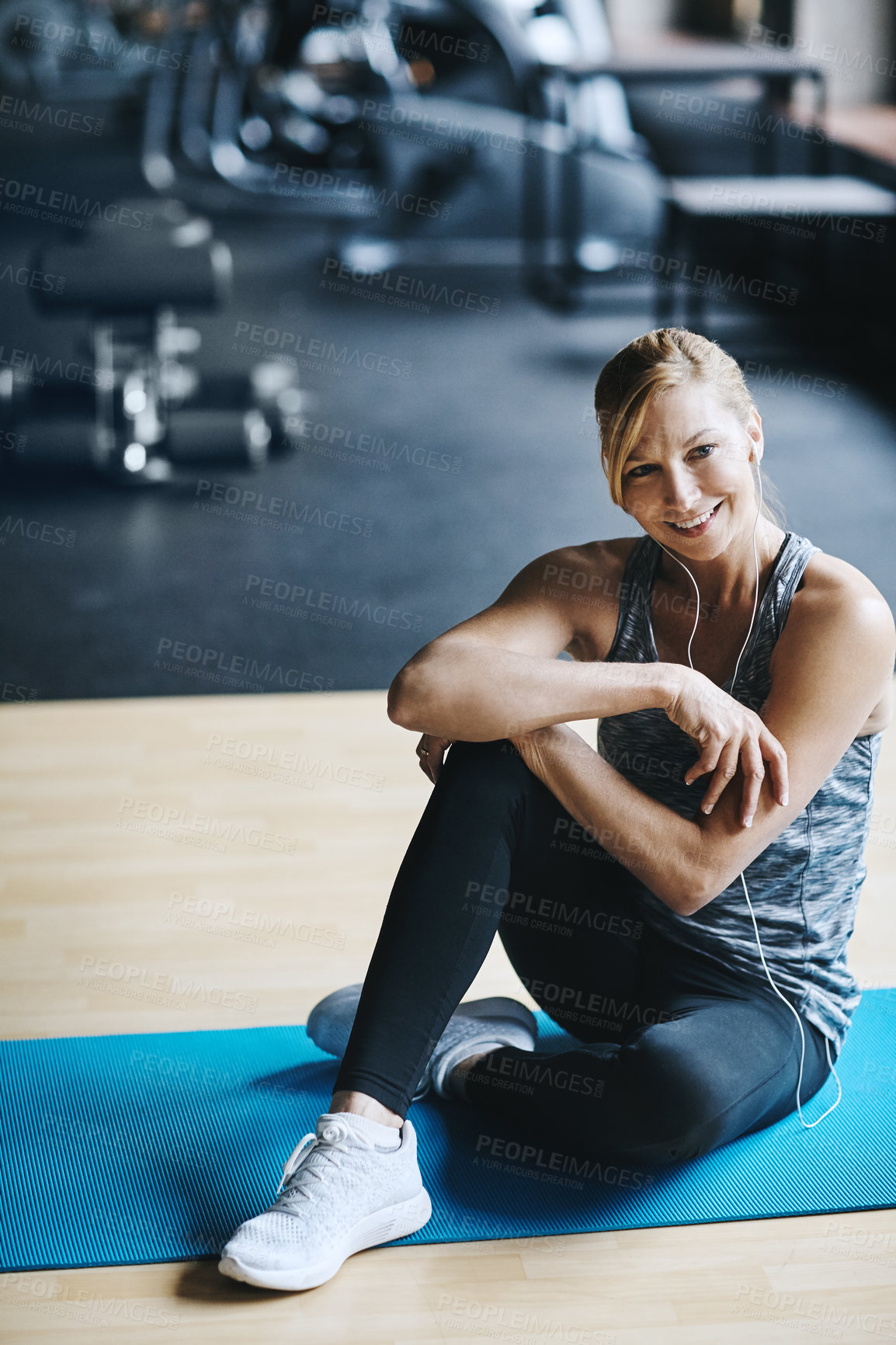 Buy stock photo Full length shot of an attractive young woman listening to music while working out in the gym