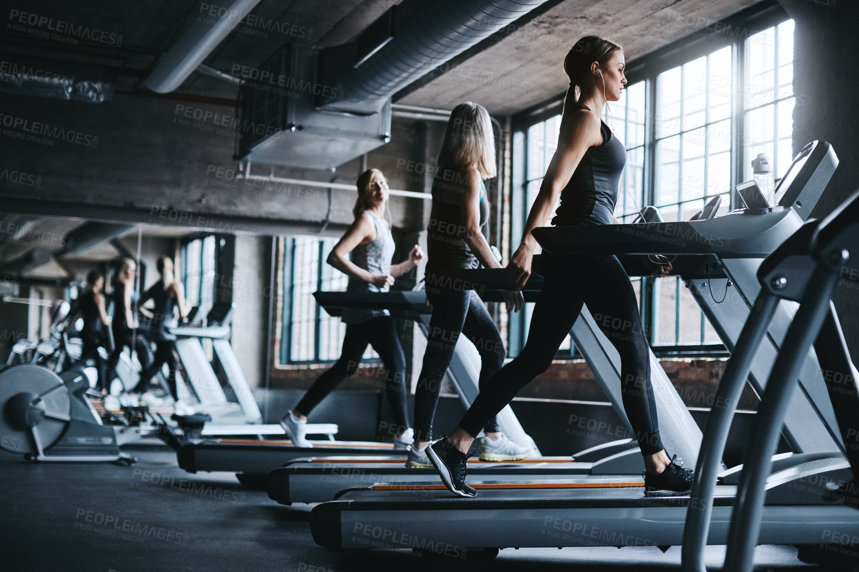 Buy stock photo Full length shot of three attractive and athletic women working out in the gym
